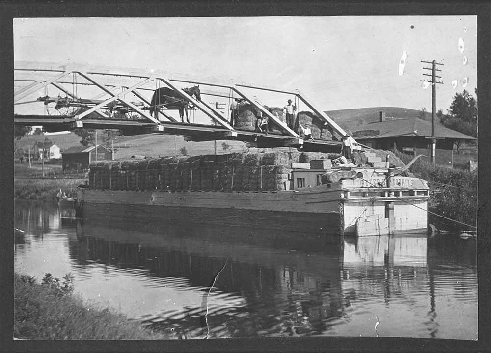 Photograph of hay being loaded from a bridge onto a canal boat at Auriesville, c. 1905 page 1
