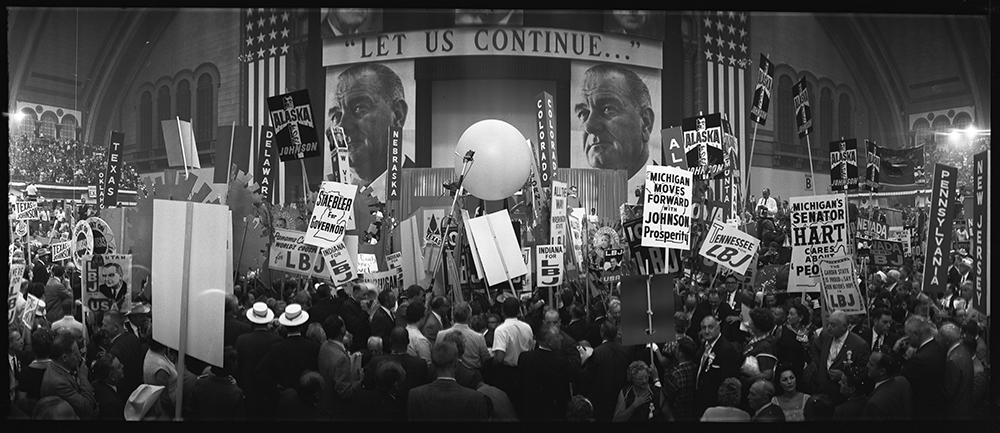 [Delegates and stage at the 1964 Democratic National Convention, Atlantic City, New Jersey; sign over stage reads "Let us continue..."] page 1